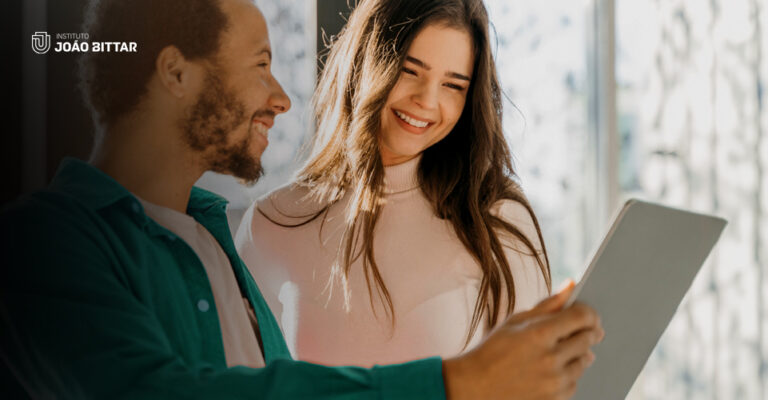 Um homem e uma mulher sorriem enquanto olham para o tablet